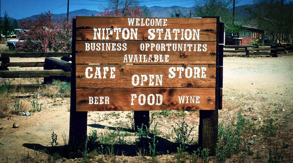 Sign welcoming newcomers to Nipton, reading as follows: Welcome Nipton Station, business opportunities available, Cafe and Store Open, Beer, Food, Wine